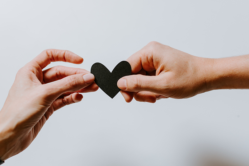 Two hands holding a black heart cut-out