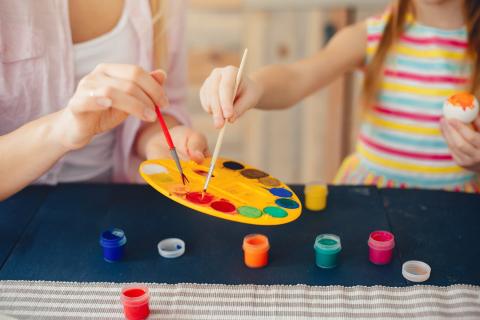 Hands and torsos of adult & child painting together