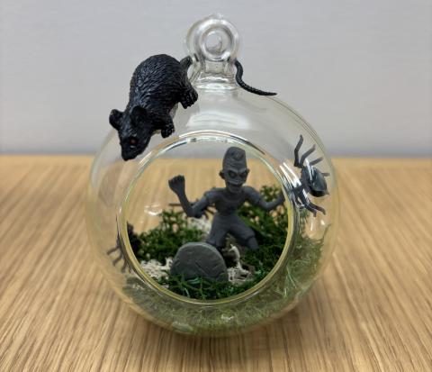 Zombie terrarium with green moss, a black rat, and gray zombie with tombstone