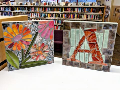 two square mosaic tiles, one with flowers and one with monogram A