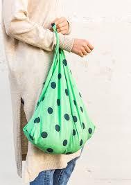 Profile view of person holding green bag with black polka dots