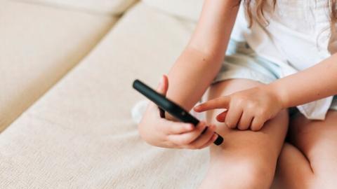 White background showing closeup of child with cell phone