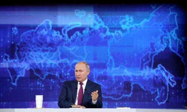 Russian President Vladimir Putin sits at a desk