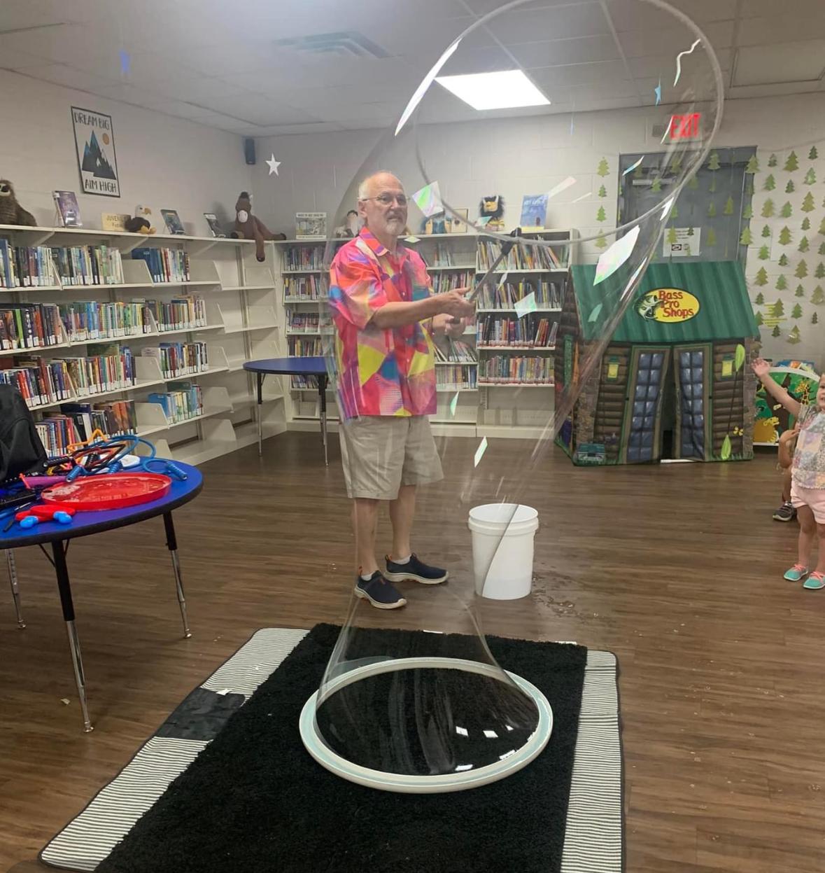 Man standing inside a life-size bubble in a library 